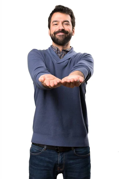 Bonito morena homem com barba segurando algo no fundo branco — Fotografia de Stock