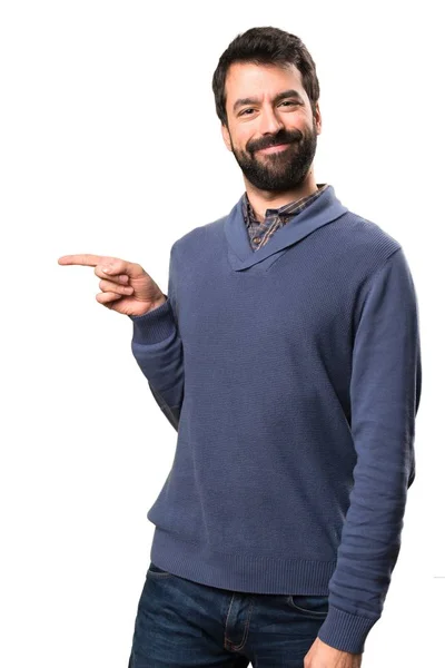 Komea brunette mies parta osoittaa sivusuunnassa valkoisella taustalla — kuvapankkivalokuva