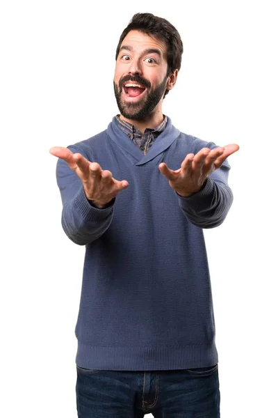 Hombre guapo morena con barba presentando algo sobre fondo blanco — Foto de Stock