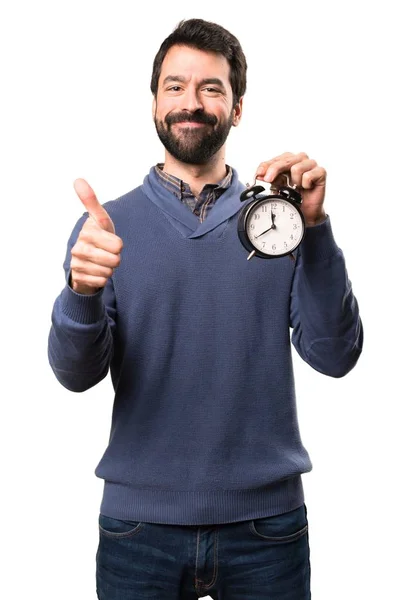 Glad snygg brunett man med skägg holding vintage klocka på vit bakgrund — Stockfoto