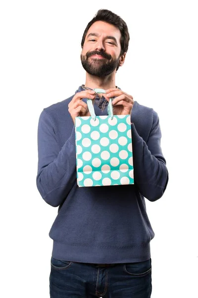 Hombre morena guapo feliz con barba con bolsa de compras sobre fondo blanco —  Fotos de Stock