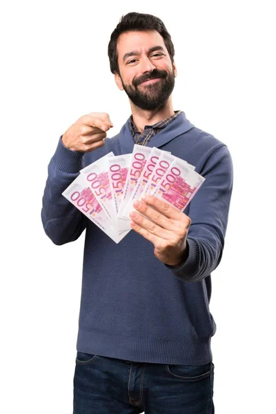 Szczęśliwy przystojny mężczyzna brunetka z brodą, biorąc dużo pieniędzy na białym tle — Zdjęcie stockowe