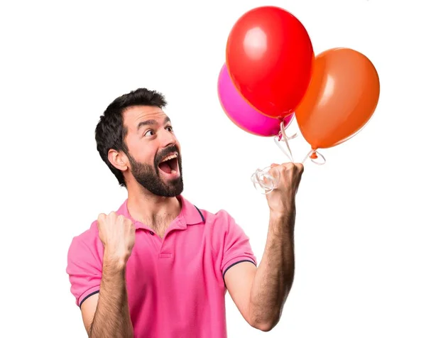 Lucky handsome young man holding balloons over isolated white background — Stock Photo, Image