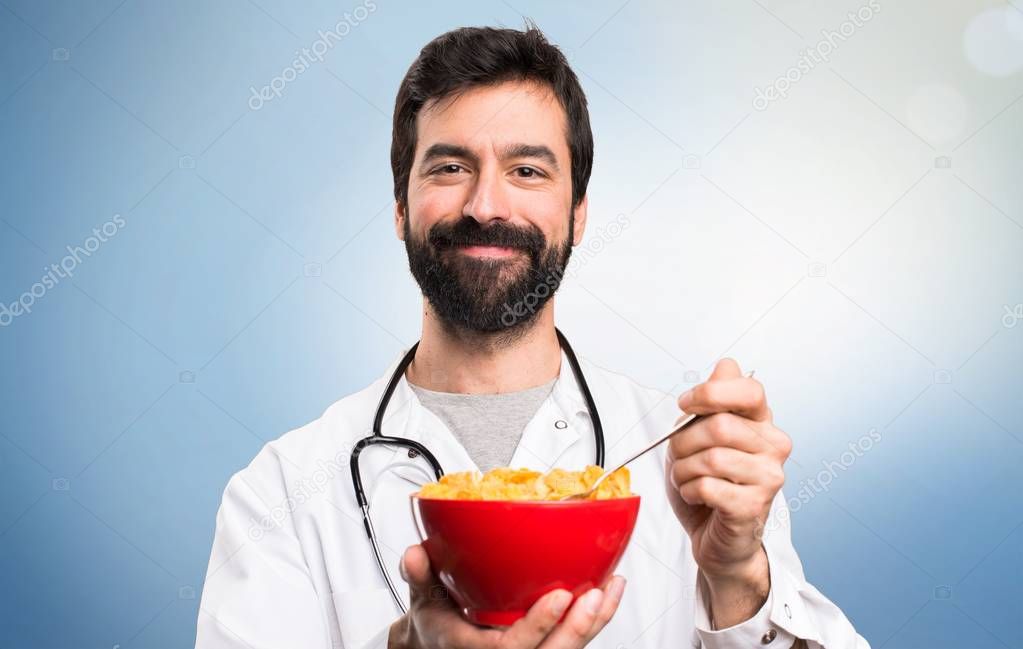 Young doctor holding a bowl of cereals on blue background