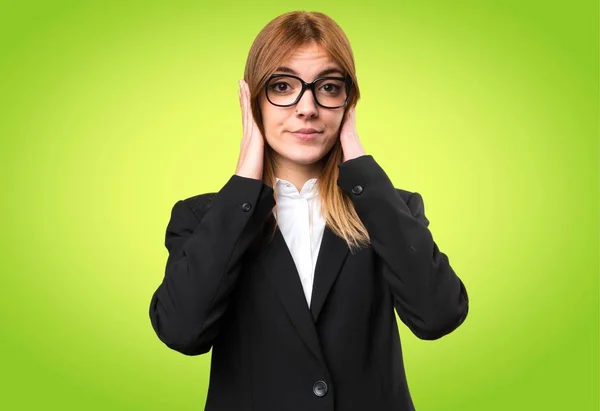 Joven mujer de negocios cubriendo sus oídos sobre fondo colorido — Foto de Stock
