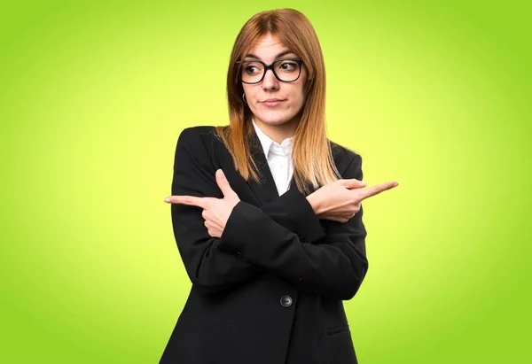 Joven mujer de negocios señalando a los laterales que tienen dudas sobre el fondo colorido —  Fotos de Stock