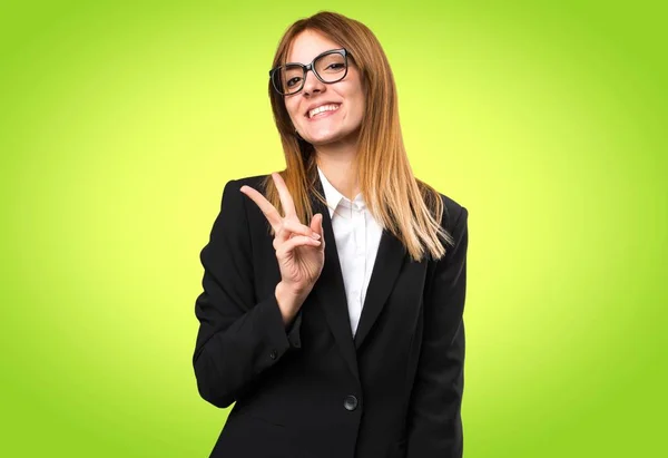 Joven mujer de negocios haciendo gesto de victoria sobre fondo colorido —  Fotos de Stock