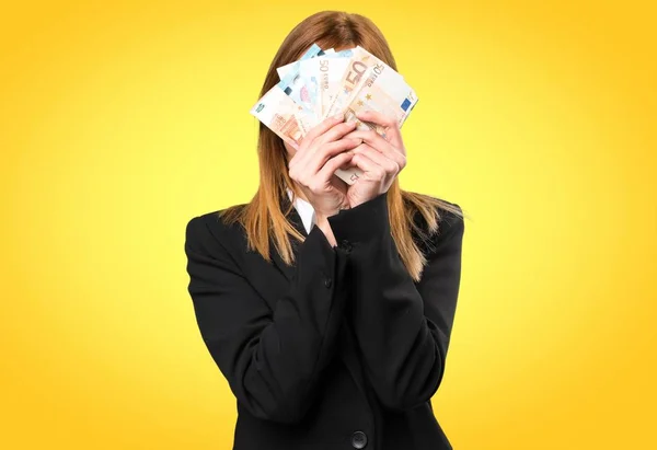 Joven mujer de negocios tomando un montón de dinero en fondo colorido — Foto de Stock
