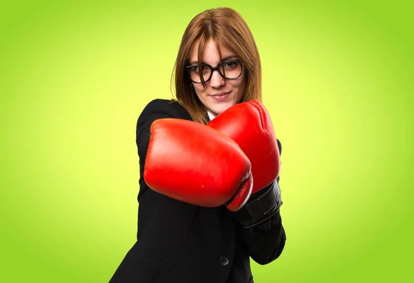 Jovem mulher de negócios com luvas de boxe em fundo colorido — Fotografia de Stock