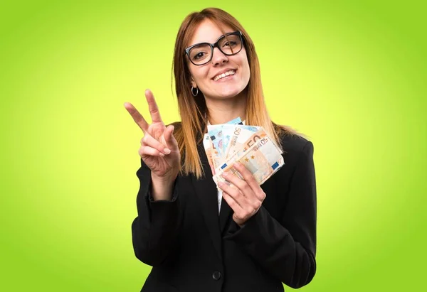 Fiatal üzleti nő vesz egy csomó pénzt, színes háttérrel — Stock Fotó