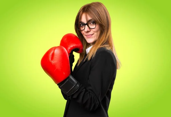 Genç iş kadını renkli arka plan üzerinde boks eldivenli — Stok fotoğraf
