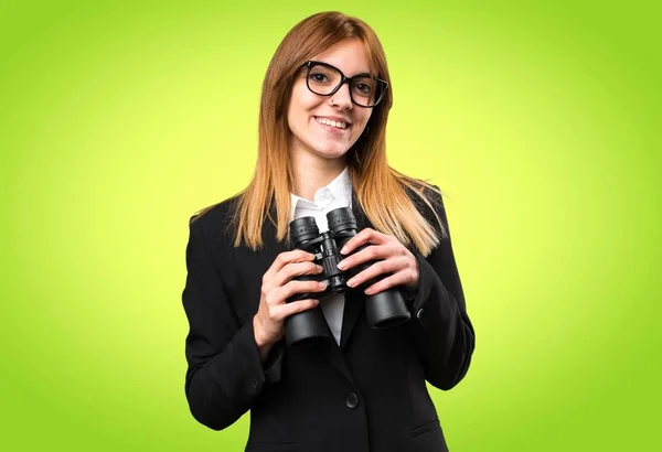 Joven mujer de negocios con prismáticos sobre fondo colorido —  Fotos de Stock