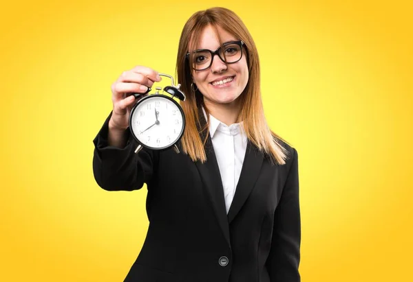 Joven mujer de negocios sosteniendo reloj vintage sobre fondo colorido — Foto de Stock