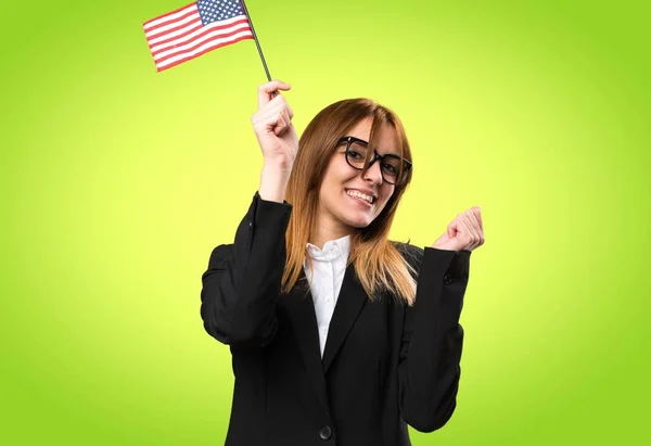 Giovane donna d'affari che tiene una bandiera americana su sfondo colorato — Foto Stock