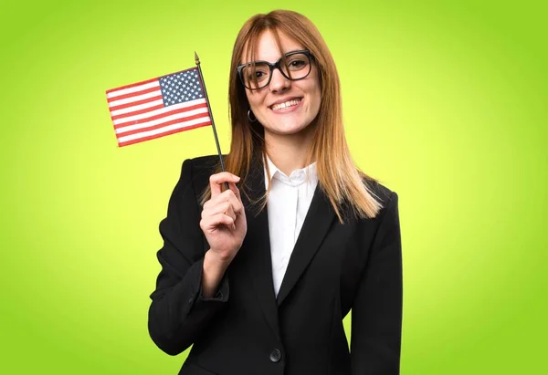 Giovane donna d'affari che tiene una bandiera americana su sfondo colorato — Foto Stock