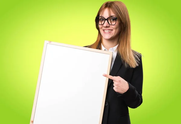 Jovem mulher de negócios segurando um cartaz vazio no fundo colorido — Fotografia de Stock