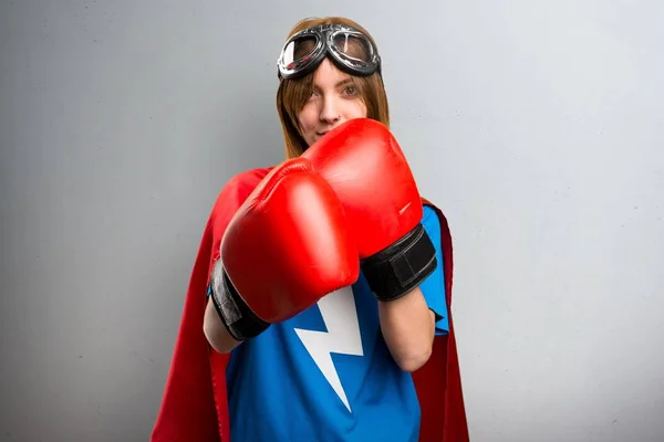 Chica superhéroe con guantes de boxeo sobre un fondo gris texturizado —  Fotos de Stock