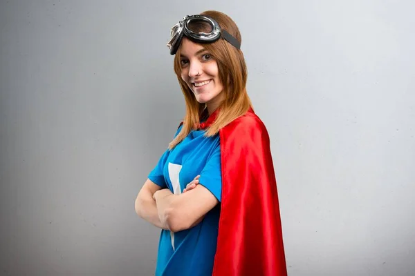 Pretty superhero girl with her arms crossed on a gray textured background — Stock Photo, Image