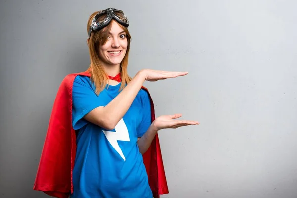 Милая супергероиня держит что-то на сером фоне — стоковое фото
