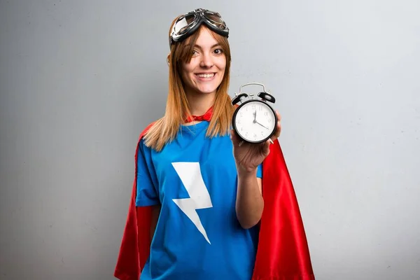 Hübsches Superheldenmädchen mit Vintage-Uhr auf grauem strukturiertem Hintergrund — Stockfoto