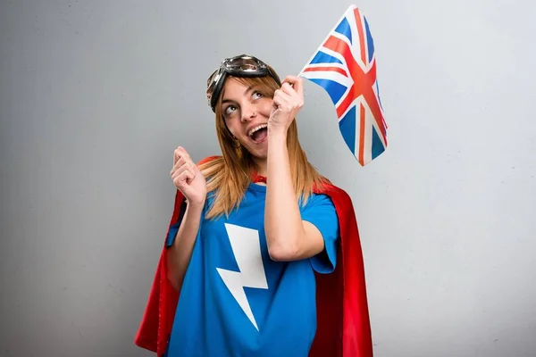 Dívka hezká superhrdina držení vlajky Spojeného království na šedý podklad s texturou — Stock fotografie