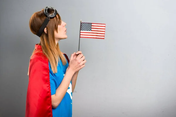 灰色のテクスチャ背景にアメリカの国旗を保持しているかなりのスーパー ヒーロー少女 — ストック写真
