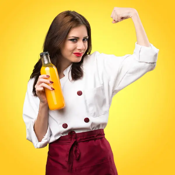 Красивая женщина шеф-повар держит апельсиновый сок на красочной backgrou — стоковое фото