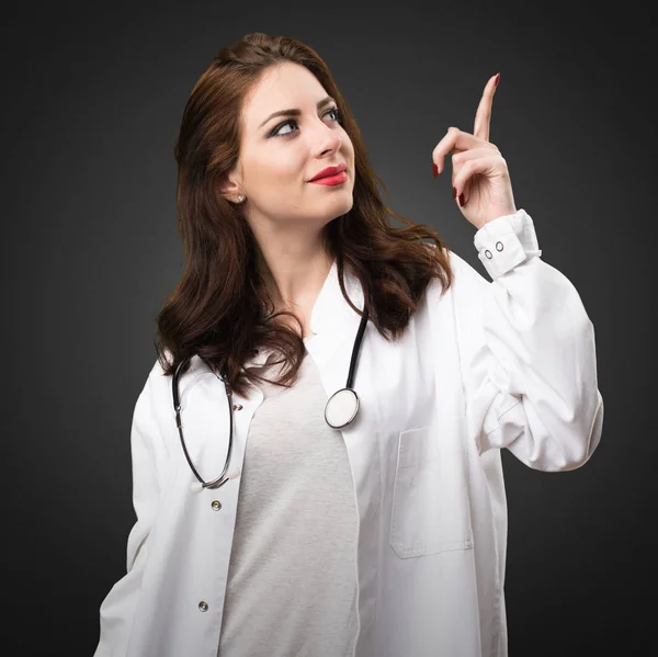 Läkare kvinna pekar uppåt på svart bakgrund — Stockfoto