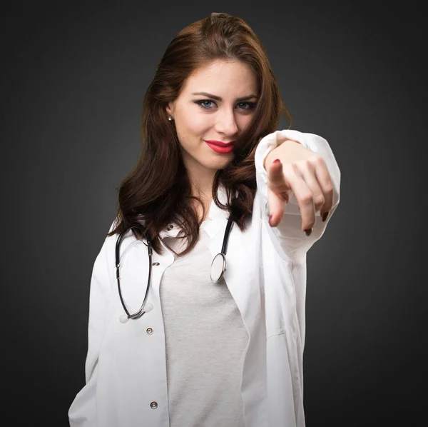 Médica mulher apontando para a frente no fundo preto — Fotografia de Stock