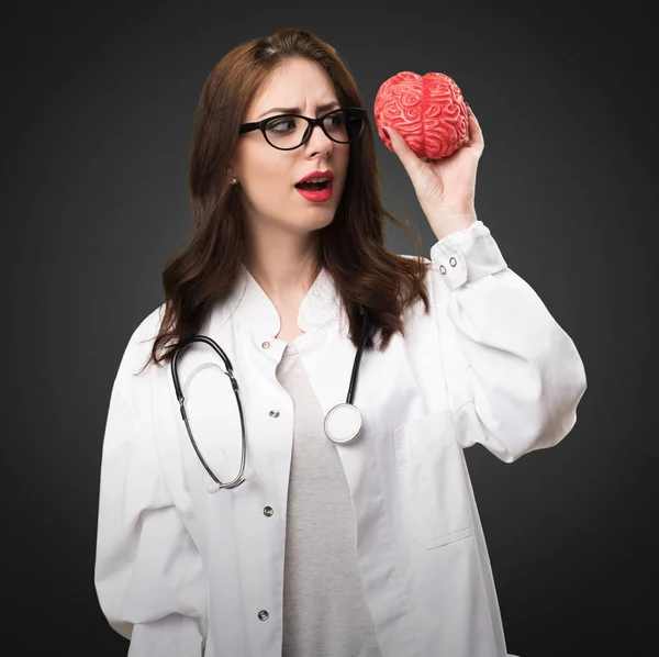 Doctor woman holding a brain on black background
