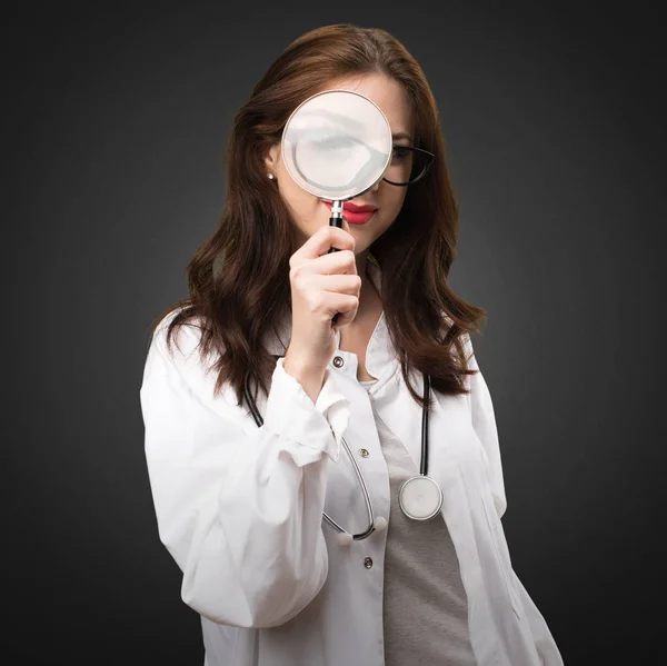 Dokter vrouw met vergrootglas op zwarte achtergrond — Stockfoto