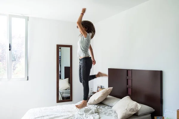 Gadis muda yang cantik melompat di tempat tidur — Stok Foto