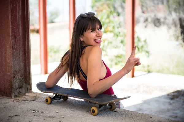 Beautiful young girl in an abandoned building with a skate — Stock Photo, Image