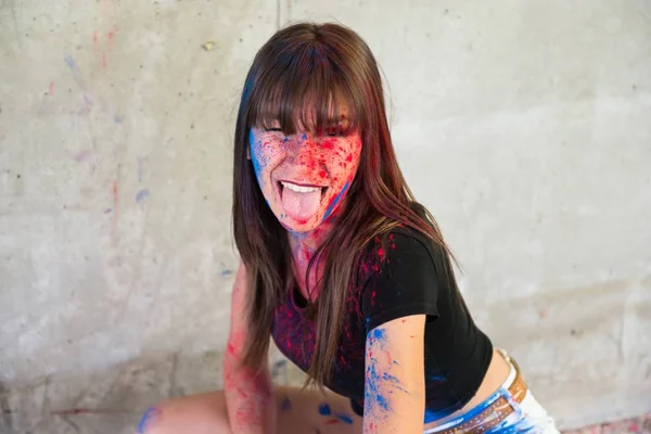 Beautiful young girl with color holi taking out her tongue — Stock Photo, Image