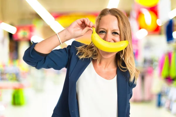 Blond tjej med banan som mustasch över vit bakgrund — Stockfoto