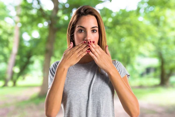 Chica joven cubriéndose la boca en el parque —  Fotos de Stock