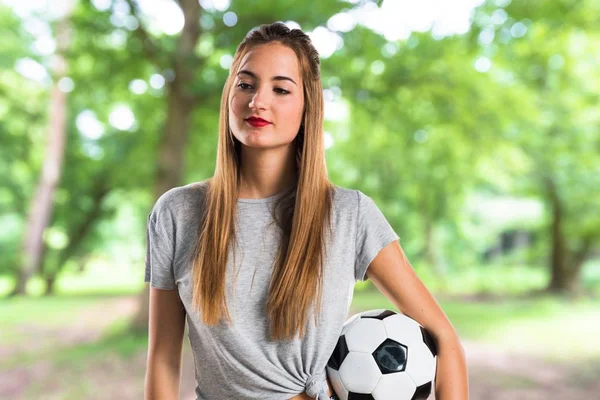 Mulher jogador segurando uma bola de futebol no parque — Fotografia de Stock