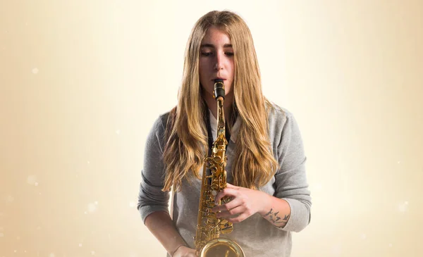 Chica tocando el saxofón sobre fondo ocre —  Fotos de Stock