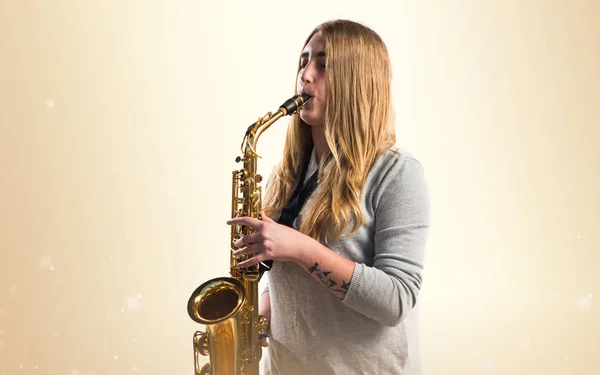 Chica tocando el saxofón sobre fondo ocre —  Fotos de Stock