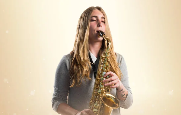 Meisje de saxofoon spelen op okergeel achtergrond — Stockfoto