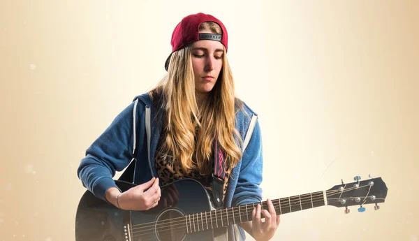 Dívka hrající kytaru na okrové pozadí — Stock fotografie