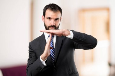 Beyaz arka plan üzerinde zaman aşımı işareti yapan genç erkek 