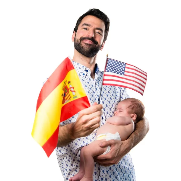 アメリカの国旗とスペイン国旗を保持している彼の生まれたばかりの赤ちゃんを持つ若い父 — ストック写真