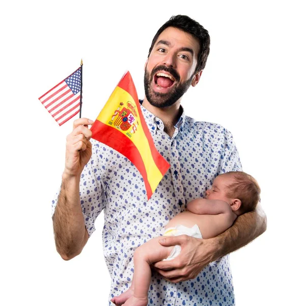 アメリカの国旗とスペイン国旗を保持している彼の生まれたばかりの赤ちゃんを持つ若い父 — ストック写真