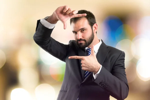 Junger Geschäftsmann macht ein Rahmenschild vor weißem Hintergrund — Stockfoto