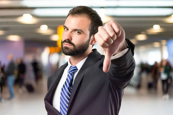 Young businessman with his thumb down over white background — Stock Photo, Image