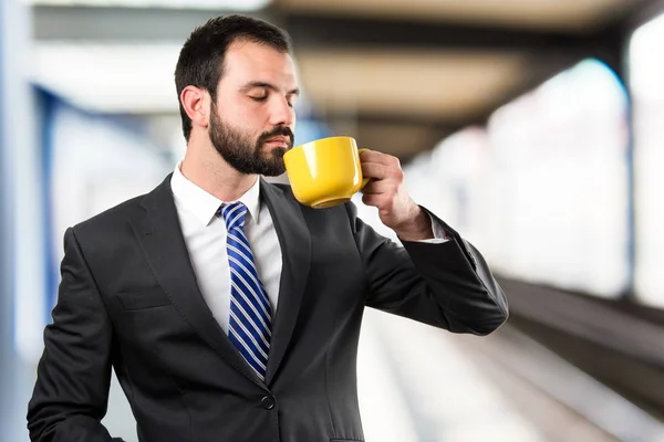 Jonge zakenman drinken een kopje koffie op witte achtergrond — Stockfoto