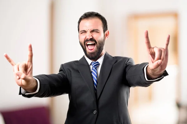 Young businessman doing the horn sign over white background — Stock Photo, Image