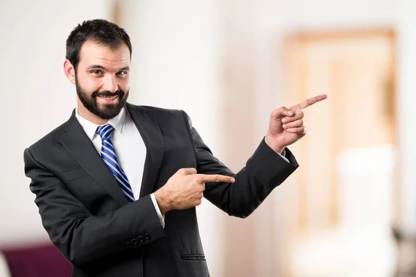 Empresario apuntando hacia un lado sobre fondo blanco — Foto de Stock