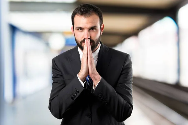 Молодий бізнесмен молиться на білому тлі — стокове фото